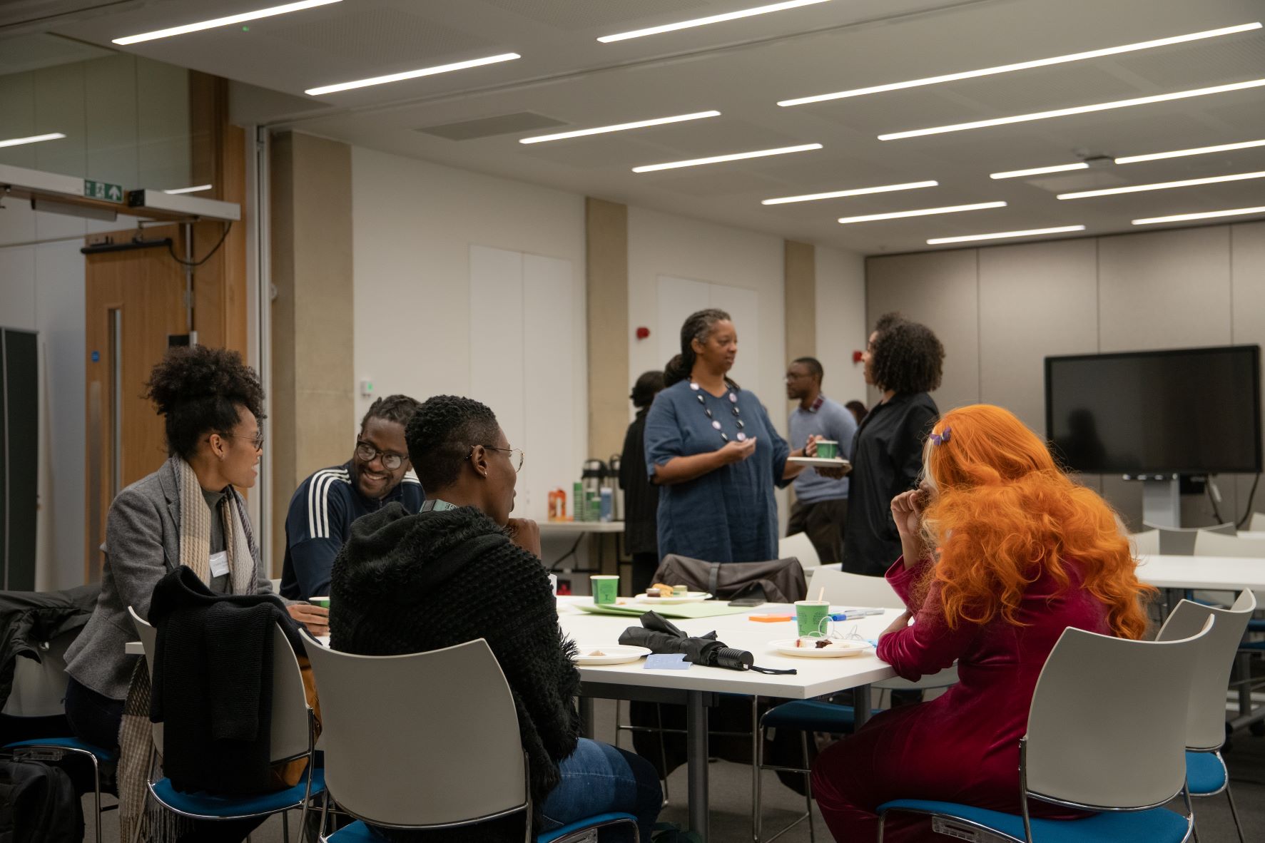 A photo of postgraduate students sharing experiences, with Sonita Alleyne (master of Jesus College and Chair of Black Advisory Hub's Steering Group) speaking to Jennifer Skinner (Library Manager of African Studies Library)